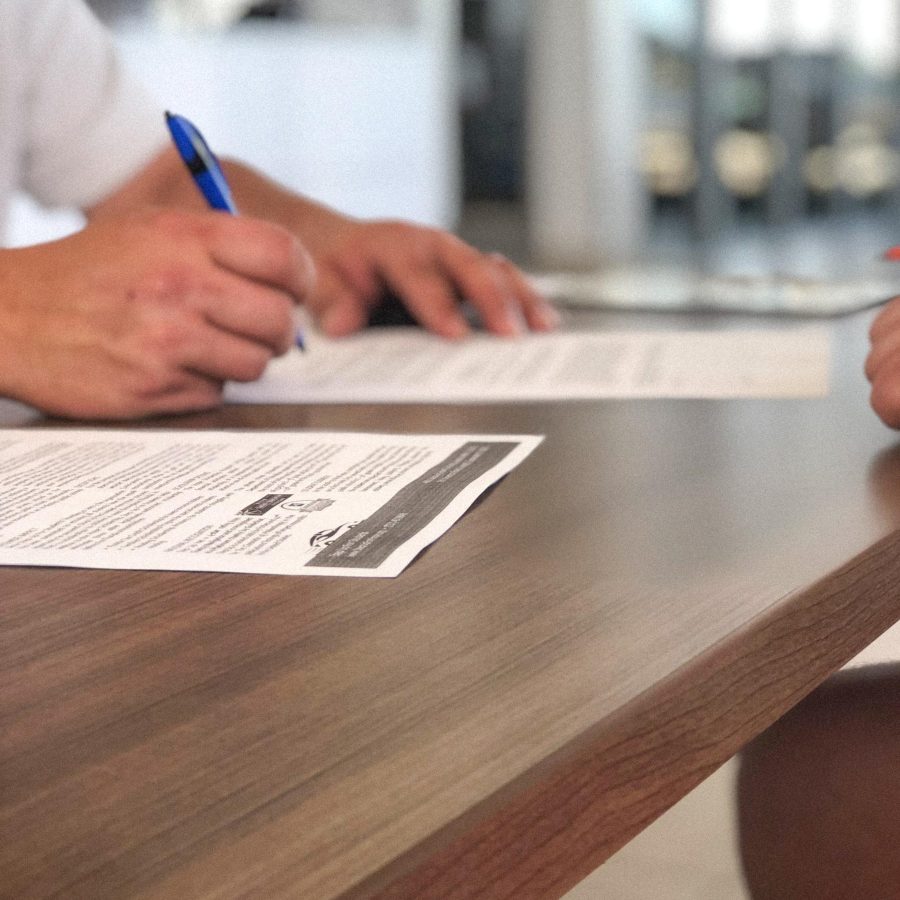 people-signing-documents-at-desk-in-office-2024-12-06-15-14-57-utc